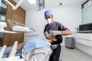 dentista de pie mientras examina la boca de un paciente en una clínica dental foto