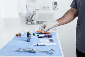 peson tomando un instrumento de una mesa con herramientas estériles para una clínica dental foto