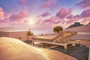 24.07.21. Santorini island, Oia sunset caldera scene, two sun beds, loungers, amazing sun rays sea view horizon colorful sky calm relax. Inspirational beach resort hotel. Luxury Greece travel vacation photo