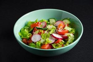 Fresh vegetable salad in a ceramic bowl on gray background.