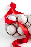 Easter eggs in a cardboard box with a red festive ribbon on a white background. photo