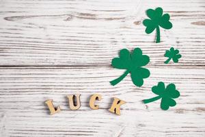 Word luck and shamrock clover leaves on a white wooden background. Happy St. Patrick's Day. photo