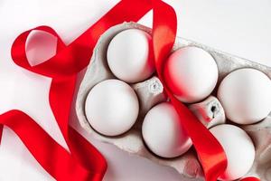 Easter eggs in a cardboard box with a red festive ribbon on a white background. photo