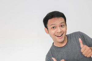 Young Asian man wear grey shirt with happy smiling face and thumbs up photo