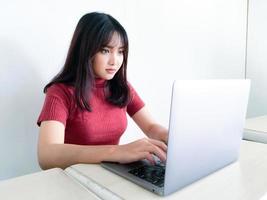 Asian beautiful girl serious or thinking in the front of laptop on the isolated white background photo