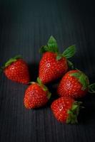 Ripe strawberries with leaves on wooden table photo