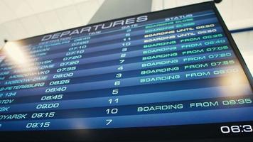 Blue departure information board at international airport for morning flights to different cities close low angle shot video