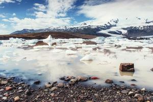 laguna glaciar iceberg fjallsarlon. las nubes blancas cumulus reflejan foto