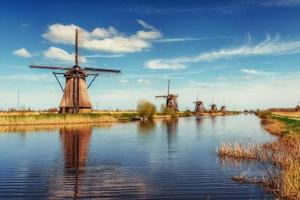 Colorful spring day with traditional Dutch windmills canal in Ro photo