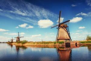 Colorful spring day with traditional Dutch windmills canal in Ro photo