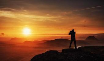 hombre feliz parado en un acantilado al atardecer foto