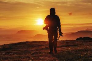 Happy man standing on a cliff at sunset photo