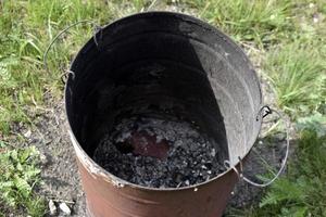 Burnt trash can on the grass in summer photo