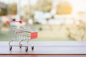 Shopping concept - empty shopping cart or trolley on brown wood table. online shopping consumers can shop from home and delivery service. with copy space