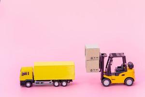logística y servicio de entrega: camión de carga, carretilla elevadora y cajas de papel o paquetes con el logotipo de un carrito de la compra sobre fondo rosa. servicio de compra en la web online y ofrece servicio a domicilio.