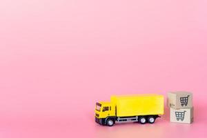 logística y servicio de entrega: camión de carga y cajas de papel o paquetes con el logotipo de un carrito de la compra sobre fondo rosa. servicio de compra en la web online y ofrece servicio a domicilio.
