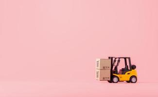 Logistics, and delivery service - Forklift model and paper cartons or parcel with a shopping cart logo on Pink background. Shopping service on The online web and offers home delivery. photo