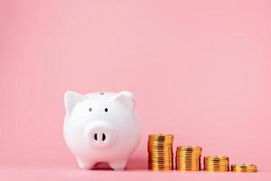 Money saving and investment concept. Piggy bank and coin stack on pink background with copy space photo