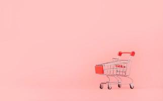 concepto de compras. carrito de compras rojo vacío sobre fondo rosa. los consumidores de compras en línea pueden comprar desde su casa y servicio de entrega. con espacio de copia foto