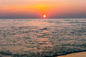 Sunset reflection sea. beautiful sunset behind the clouds and blue sky above the over sea landscape background photo