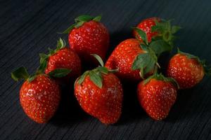 Ripe strawberries with leaves on wooden table photo