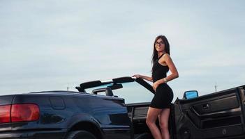 hermosa mujer cerca de convertible negro foto