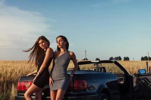 Two sexy brunette woman standing near her car photo