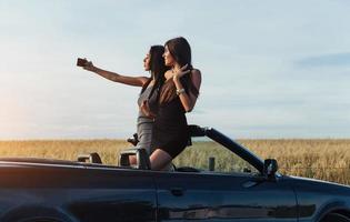 Two sexy brunette woman standing near cabriolet photo