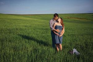 familia feliz abrazándose en un campo de trigo verde foto