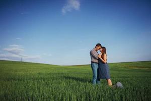 Happy family hugging in a field of green wheat photo