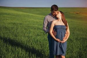 Happy family hugging in a field of green wheat photo