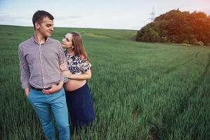 Happy family hugging in a field of green wheat photo