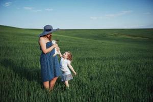 Happy mother and baby with rabbit on hands in field photo
