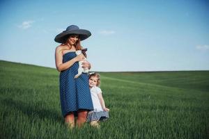 Happy mother and baby with rabbit on hands in field photo