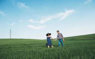 familia feliz abrazándose en un campo de trigo verde foto