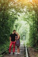 pareja amorosa en un túnel de árboles verdes en el ferrocarril foto
