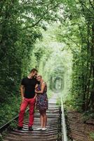 Loving couple in a tunnel of green trees on railroad photo