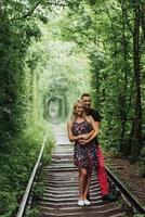 Loving couple in a tunnel of green trees on railroad photo