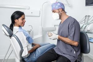 dentista mostrando un molde dental a un paciente sentado en una clínica dental. foto