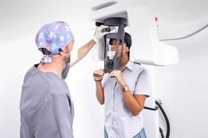 dentista graduando una máquina de blanqueamiento dental utilizada por un paciente en una clínica dental foto