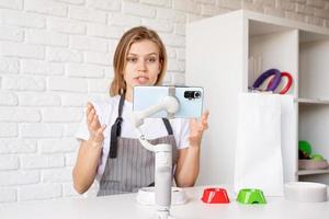 Young woman groomer blogger speaking looking to camera, talking about dog food and pet care equipment photo