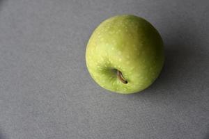 una manzana verde sobre un fondo gris foto