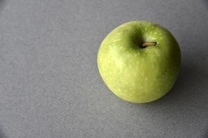 una manzana verde sobre un fondo gris foto