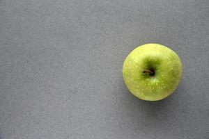A green apple on a gray background photo