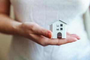 mujer mujer manos sosteniendo una pequeña casa de juguete blanca en miniatura. sueño de seguro de propiedad hipotecaria mudanza de casa y concepto de bienes raíces.
