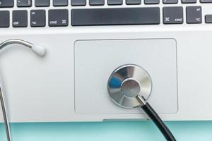 Stethoscope keyboard laptop computer isolated on blue background. Modern medical Information technology and sofware advances concept. Computer and gadget diagnostics and repair photo