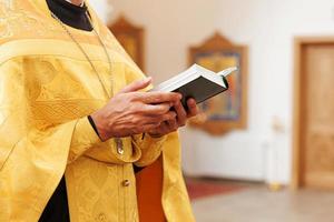 Iglesia Ortodoxa. cristiandad. manos de sacerdote sosteniendo el libro sagrado de la biblia en el fondo tradicional de la iglesia ortodoxa el día de la boda, la víspera de pascua o la celebración de navidad. religión fe orar símbolo foto