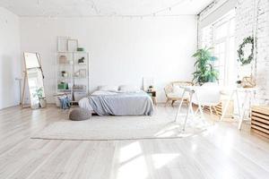 Stylish loft bedroom interior. Spacious design apartment with light walls large windows big bed. Clean modern decoration with elegant furniture in minimalist Scandinavian style. photo