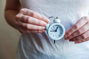 Female woman hands holding ringing twin bell vintage classic alarm clock. Rest hours time of life good morning night wake up awake concept. photo