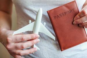 Tourist essentials. Female woman hands holding small toy model plane and passport. Travel by plane vacation summer weekend sea adventure trip journey ticket tour concept.
